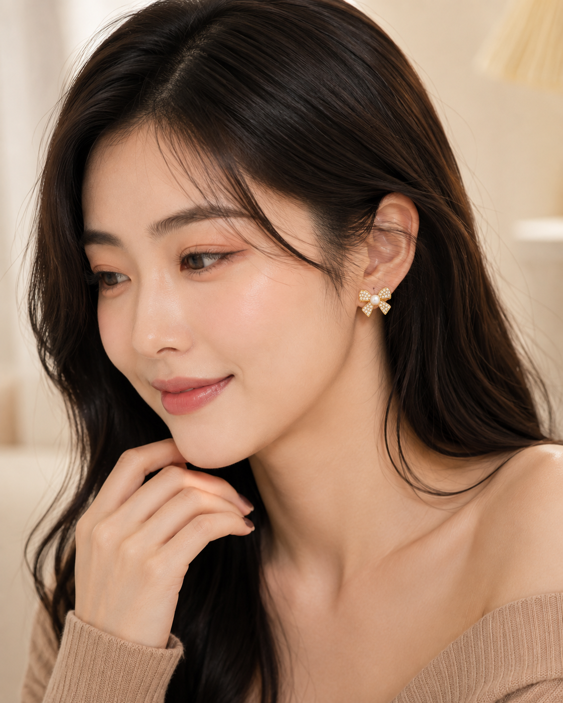 ELORIA model wearing gold-tone crystal bow earrings with pearl center