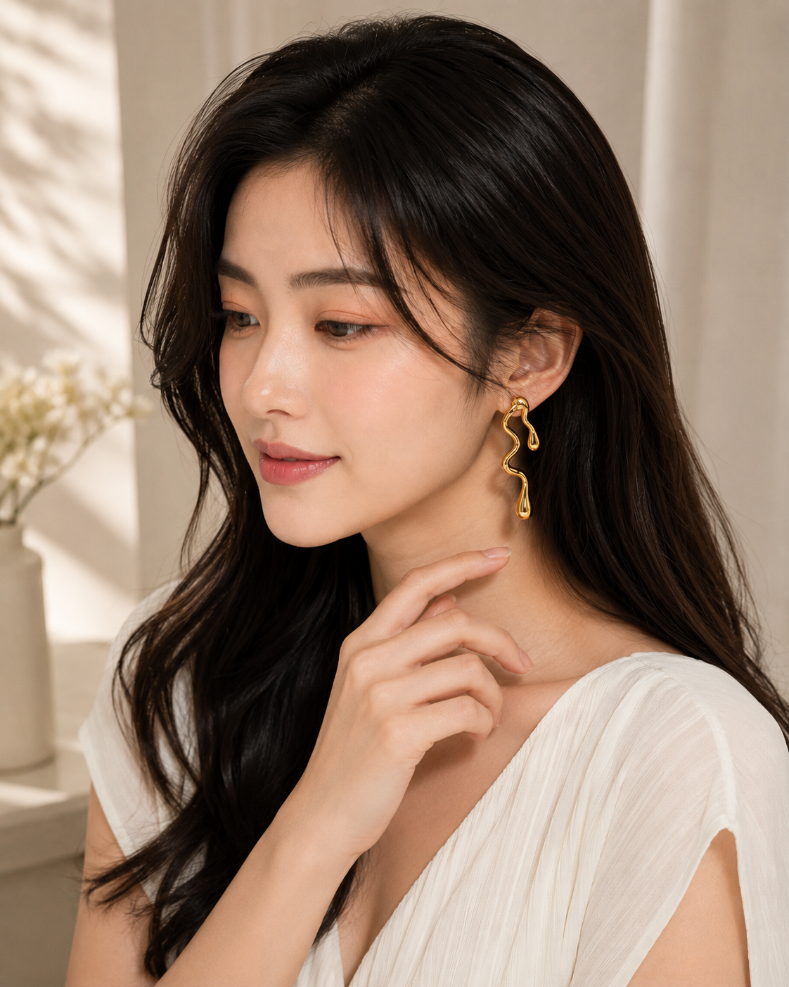 Woman wearing ELORIA Aurelia Wave gold-tone drop earrings