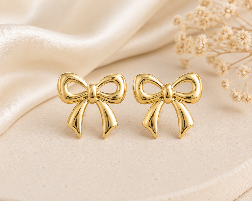 Golden bow earrings with polished gold finish on ivory satin