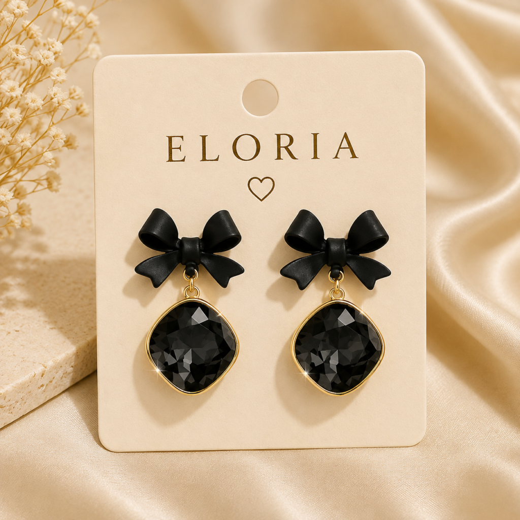 ELORIA black bow crystal drop earrings on a cream display card