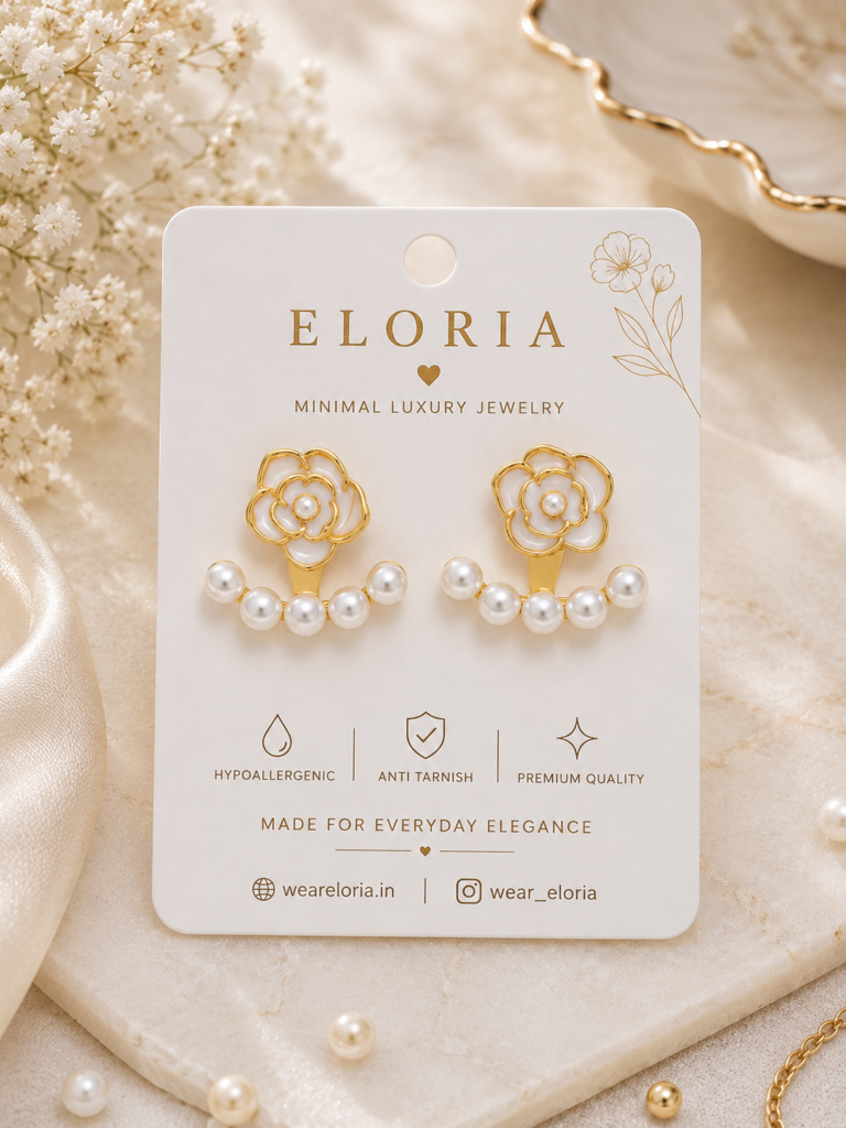Gold floral earrings with white pearl detailing on an elegant jewelry display surface